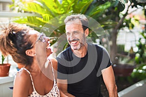 Middle age beautiful couple sitting on terrace speaking and smiling