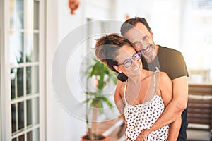 Middle age beautiful couple standing on terrace hugging and smiling