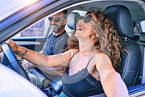 Middle age beautiful couple on vacation wearing sunglasses smiling happy driving car