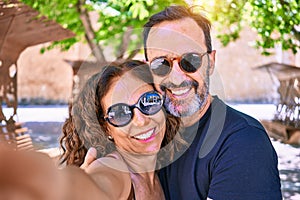 Middle age beautiful couple wearing casual clothes and sunglasses smiling happy