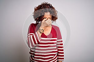 Middle age beautiful curly hair woman wearing casual striped sweater over white background tired rubbing nose and eyes feeling