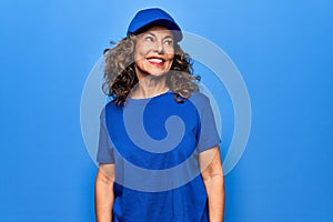 Middle age beautiful delivery woman wearing blue uniform and cap over isolated background looking to side, relax profile pose with