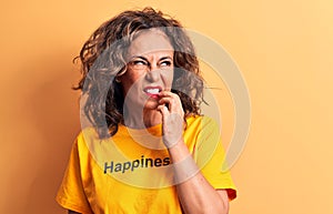 Middle age beautiful woman wearing t-shirt with happiness word over yellow background thinking concentrated about doubt with