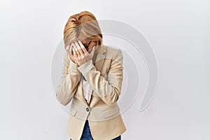 Middle age blonde business woman standing over isolated background with sad expression covering face with hands while crying