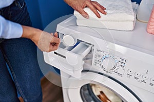 Middle age blonde woman pouring detergent on washing machine at laundry room