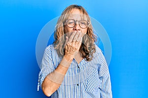 Middle age blonde woman wearing casual clothes and glasses bored yawning tired covering mouth with hand