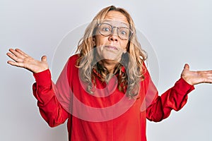 Middle age blonde woman wearing casual clothes and glasses clueless and confused with open arms, no idea and doubtful face