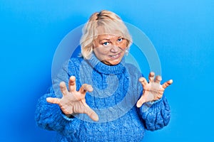 Middle age blonde woman wearing casual clothes smiling funny doing claw gesture as cat, aggressive and sexy expression