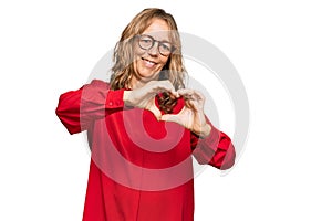 Middle age blonde woman wearing casual shirt over red background smiling in love doing heart symbol shape with hands