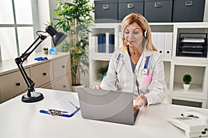 Middle age blonde woman wearing doctor uniform having medical teleconsultation at clinic