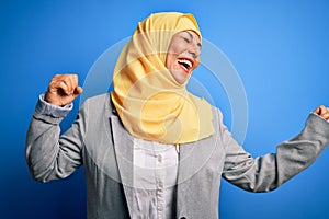 Middle age brunette business woman wearing muslim traditional hijab over blue background Dancing happy and cheerful, smiling