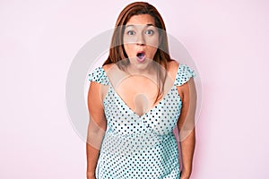 Middle age brunette hispanic woman wearing summer dress scared and amazed with open mouth for surprise, disbelief face