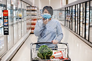 Middle age brunette woman shopping in grocery store supermarket and talking on audio chat phone. New social media chat app.