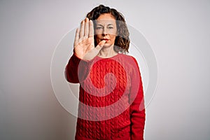 Middle age brunette woman wearing casual sweater standing over isolated white background doing stop sing with palm of the hand
