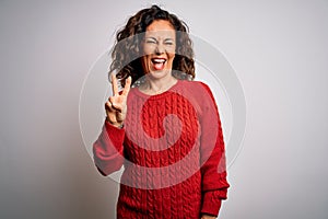 Middle age brunette woman wearing casual sweater standing over isolated white background smiling with happy face winking at the