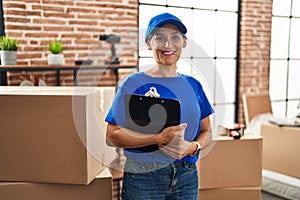 Middle age brunette woman wearing delivery uniform at house moving looking positive and happy standing and smiling with a