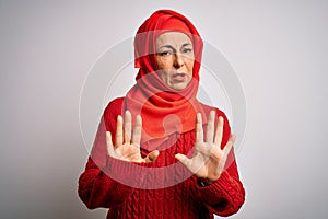 Middle age brunette woman wearing muslim traditional hijab over isolated white background Moving away hands palms showing refusal