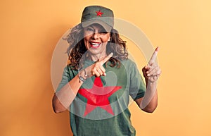 Middle age brunette woman wearing t-shirt and cap with red star symbol of communism smiling and looking at the camera pointing