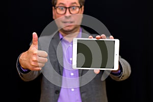 Middle age Business man holding and shows thumb up at pc with blank screen