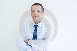 Middle age business man looking natural and relaxed with crossed arms over white wall background