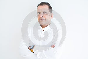 Middle age business man looking natural and relaxed with crossed arms over white wall background