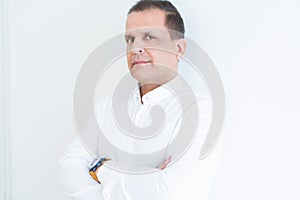 Middle age business man looking natural and relaxed with crossed arms over white wall background