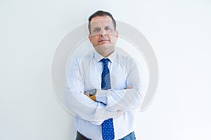 Middle age business man looking natural and relaxed with crossed arms over white wall background