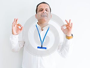 Middle age business man wearing ID card over white background relax and smiling with eyes closed doing meditation gesture with