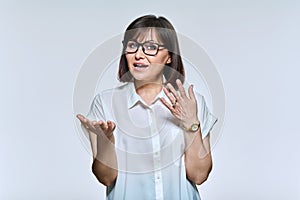 Middle age business woman in glasses talking, looking at camera, on light background