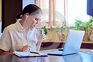 Middle age business woman in headphones using laptop for video conference