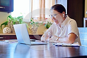 Middle age business woman in headphones using laptop for video conference