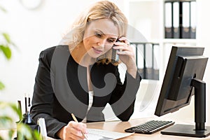 Middle-age business woman talking on the mobile phone in office. Portrait of smiling business woman.
