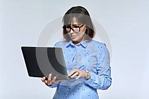 Middle age business woman using laptop, on light background