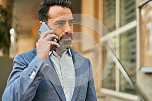 Middle age businessman with serious expresison talking on the smartphone at the city