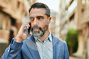 Middle age businessman with serious expresison talking on the smartphone at the city