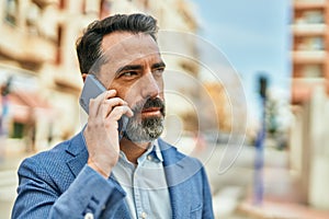 Middle age businessman with serious expresison talking on the smartphone at the city