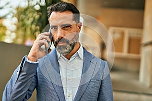 Middle age businessman with serious expresison talking on the smartphone at the city