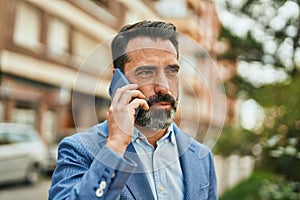 Middle age businessman with serious expresison talking on the smartphone at the city