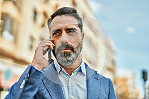 Middle age businessman with serious expresison talking on the smartphone at the city