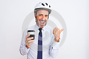 Middle age businessman wearing bike helmet drinking coffee over isolated white background pointing and showing with thumb up to