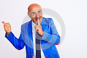 Middle age businessman wearing suit standing over isolated white background asking to be quiet with finger on lips pointing with