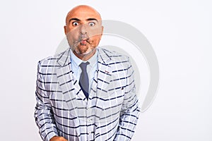 Middle age businessman wearing suit standing over isolated white background making fish face with lips, crazy and comical gesture