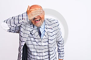 Middle age businessman wearing suit standing over isolated white background smiling and laughing with hand on face covering eyes