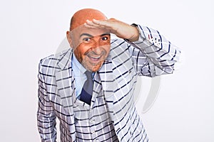 Middle age businessman wearing suit standing over isolated white background very happy and smiling looking far away with hand over