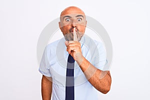 Middle age businessman wearing tie standing over isolated white background asking to be quiet with finger on lips