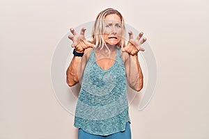 Middle age caucasian blonde woman wearing sportswear smiling funny doing claw gesture as cat, aggressive and sexy expression