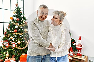 Middle age caucasian couple smiling happy and hugging celebrating christmas at home