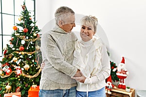 Middle age caucasian couple smiling happy and hugging celebrating christmas at home