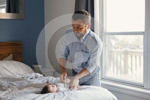 Middle age Caucasian father changing diaper clothes for newborn baby daughter son. Man parent taking care of a child at home.