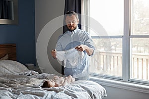 Middle age Caucasian father changing diaper clothes for newborn baby daughter son. Man parent taking care of a child at home.